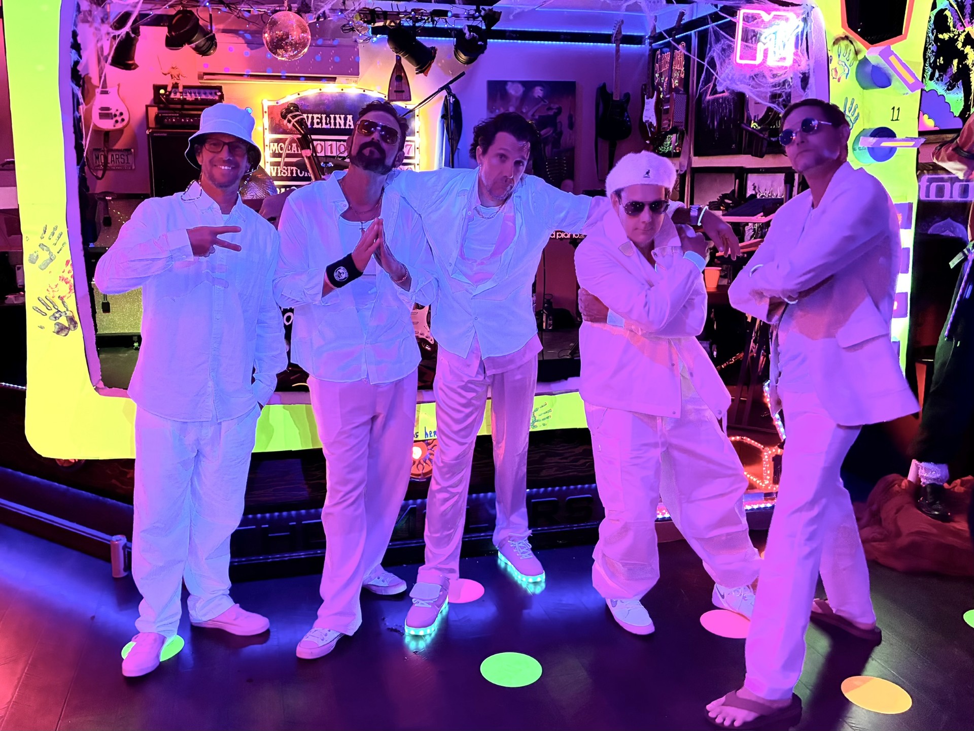 The Molars band posing together in white costumes on their performance stage